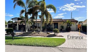 A residential property with a paved entrance, palm trees, and a clear blue sky. - Luxurious little home! (Hialeah)