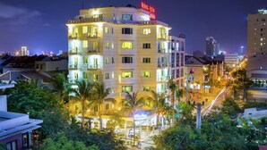 A multi-story hotel with balconies and a rooftop terrace, surrounded by greenery and urban buildings. - Cocochine a VIE Collection (Da Nang Municipality)