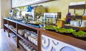 A buffet setup with multiple coffee machines, a variety of bowls and plates, and a wicker basket. - Cocochine a VIE Collection (Da Nang)