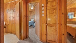 A wooden hallway with a bed and a bathroom visible in the background. - Rivers Resort Cabin #2 (Strawberry)