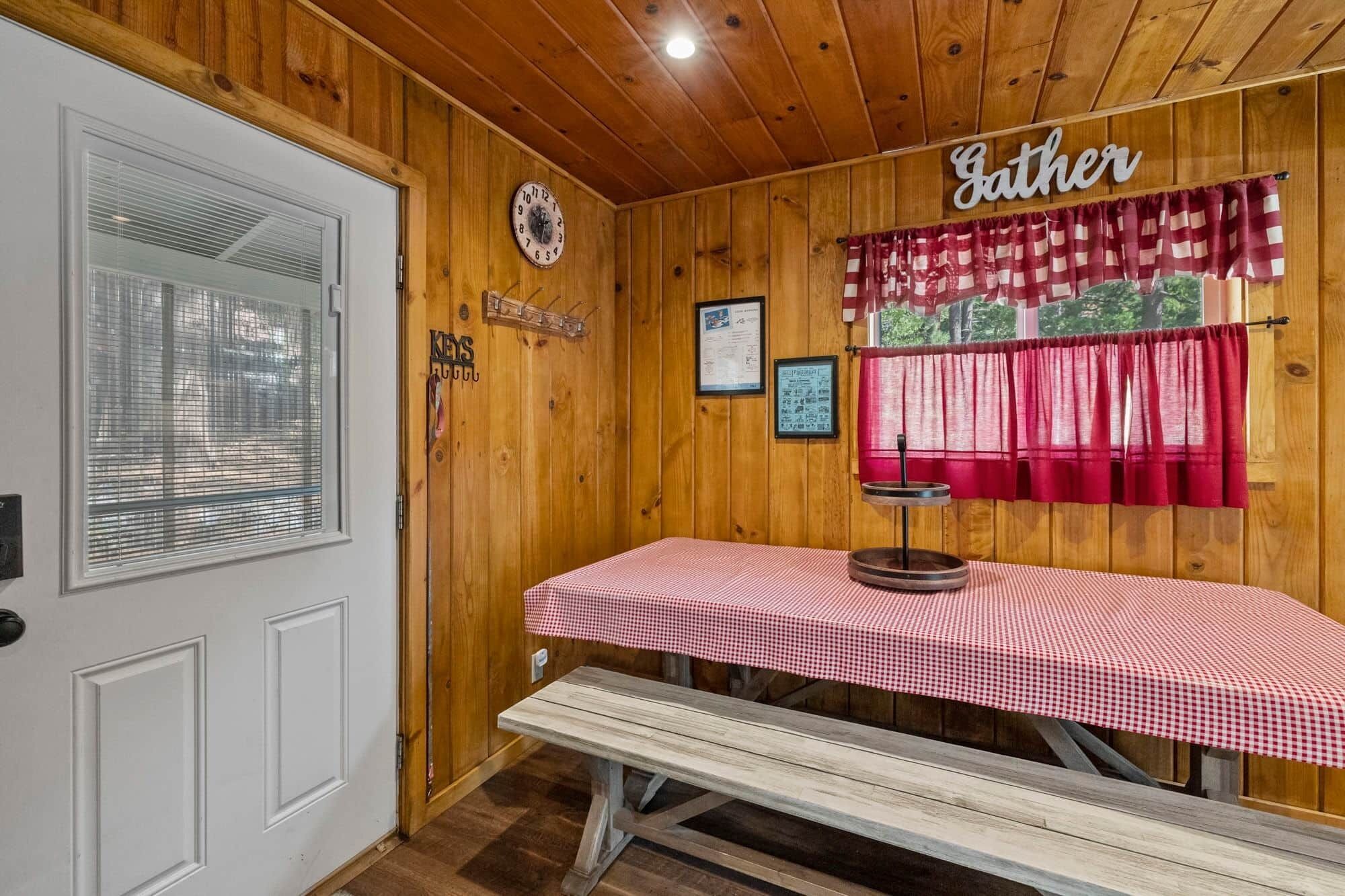 Un intérieur en bois avec un banc et une table recouverte d’une nappe à carreaux.