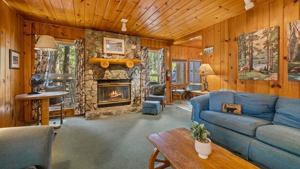 A cozy cabin interior with a stone fireplace, wooden walls, and a blue sofa.