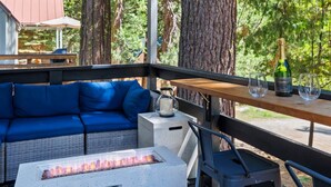 Un área de estar al aire libre con un sofá azul, una chimenea y una mesa con una botella y copas.