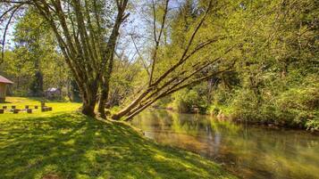 Un parc au bord de la rivière, doté d’un espace pique-nique et d’une structure en bois.