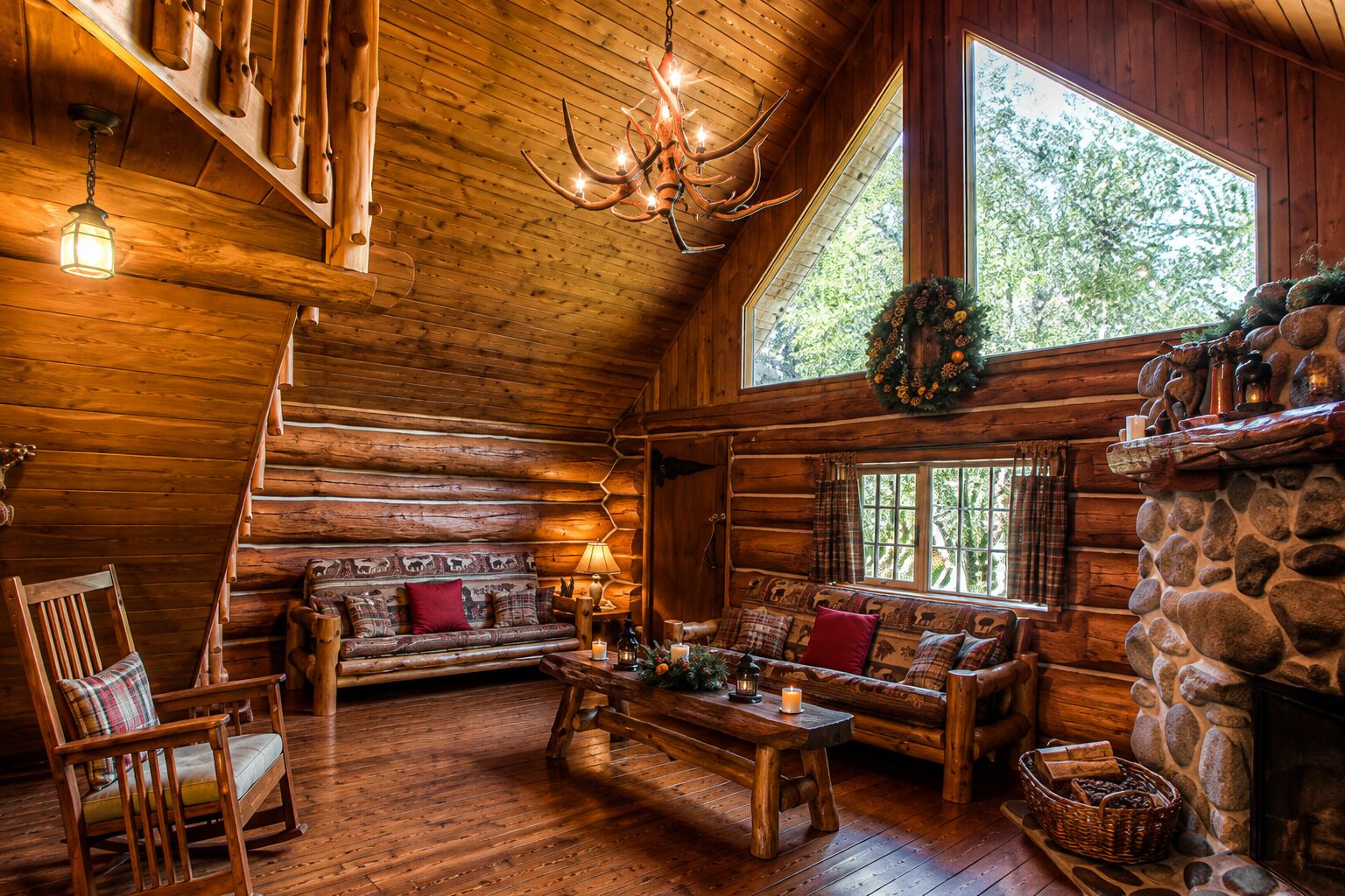 A log cabin interior with a fireplace, wooden furniture, and a chandelier.
