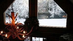 A chandelier in a room with a view of a snowy landscape through a window.
