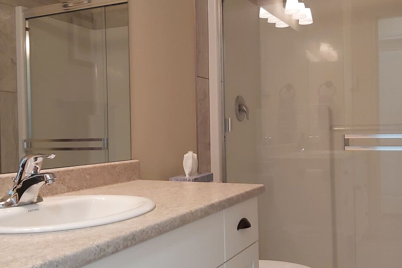 A bathroom with a sink, mirror, and shower.