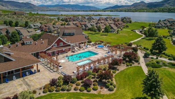 Un quartier résidentiel avec des maisons, une piscine et une vue sur un lac et des montagnes.