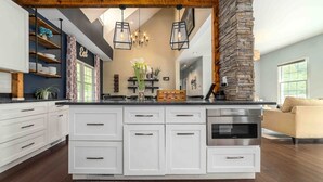 Cozinha moderna com armários brancos, uma ilha grande e uma parede decorativa em pedra.
