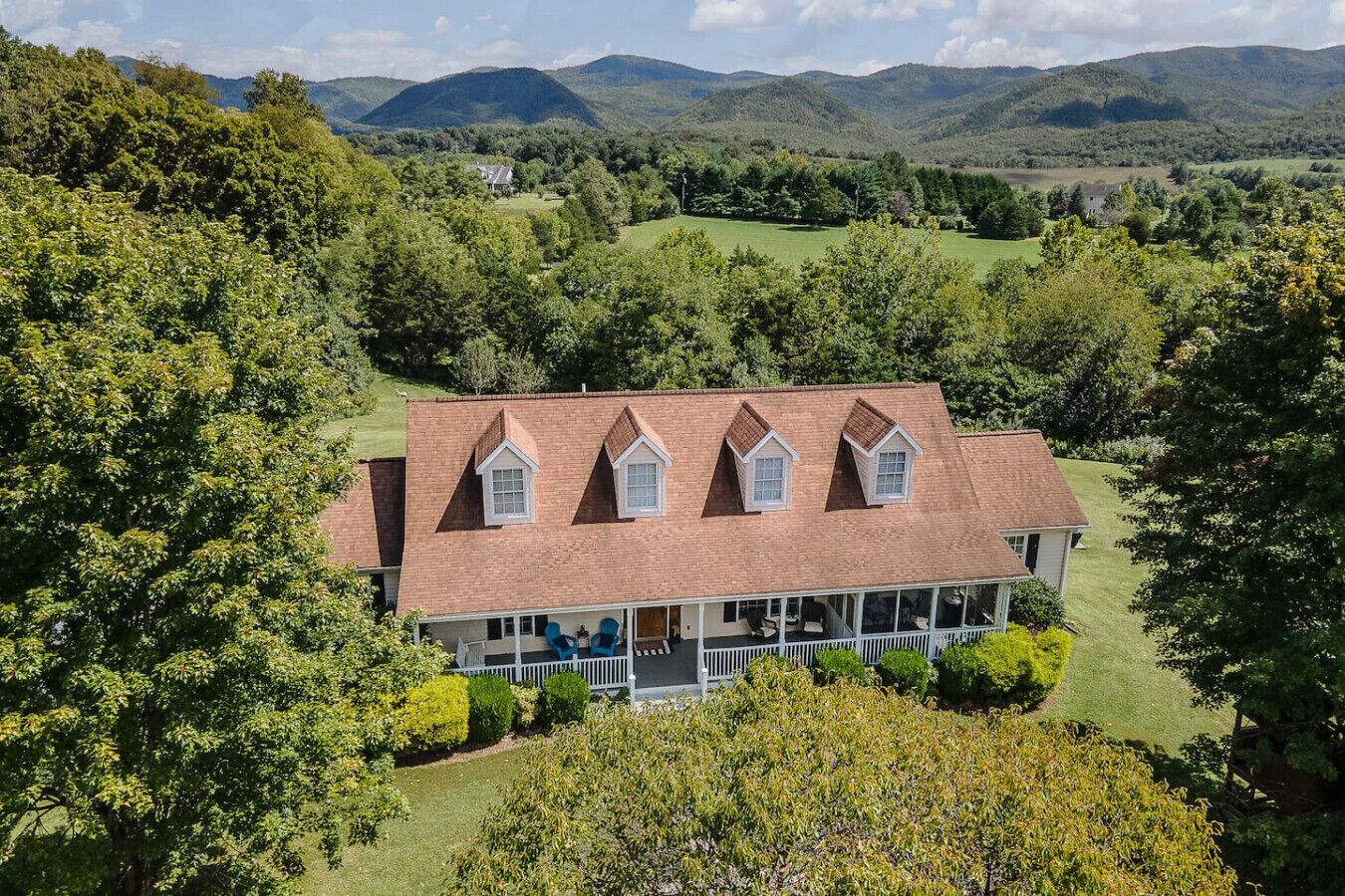 A large house with a wrap-around porch, multiple windows, and a well-maintained lawn.