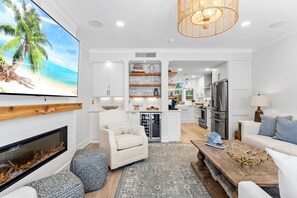 A modern living room with a fireplace, a large flat-screen TV, a dining area, and a kitchen. - "Beachwalk Landing" Perfect in Every Way!  Includes Cart for Your Stay (Destin)