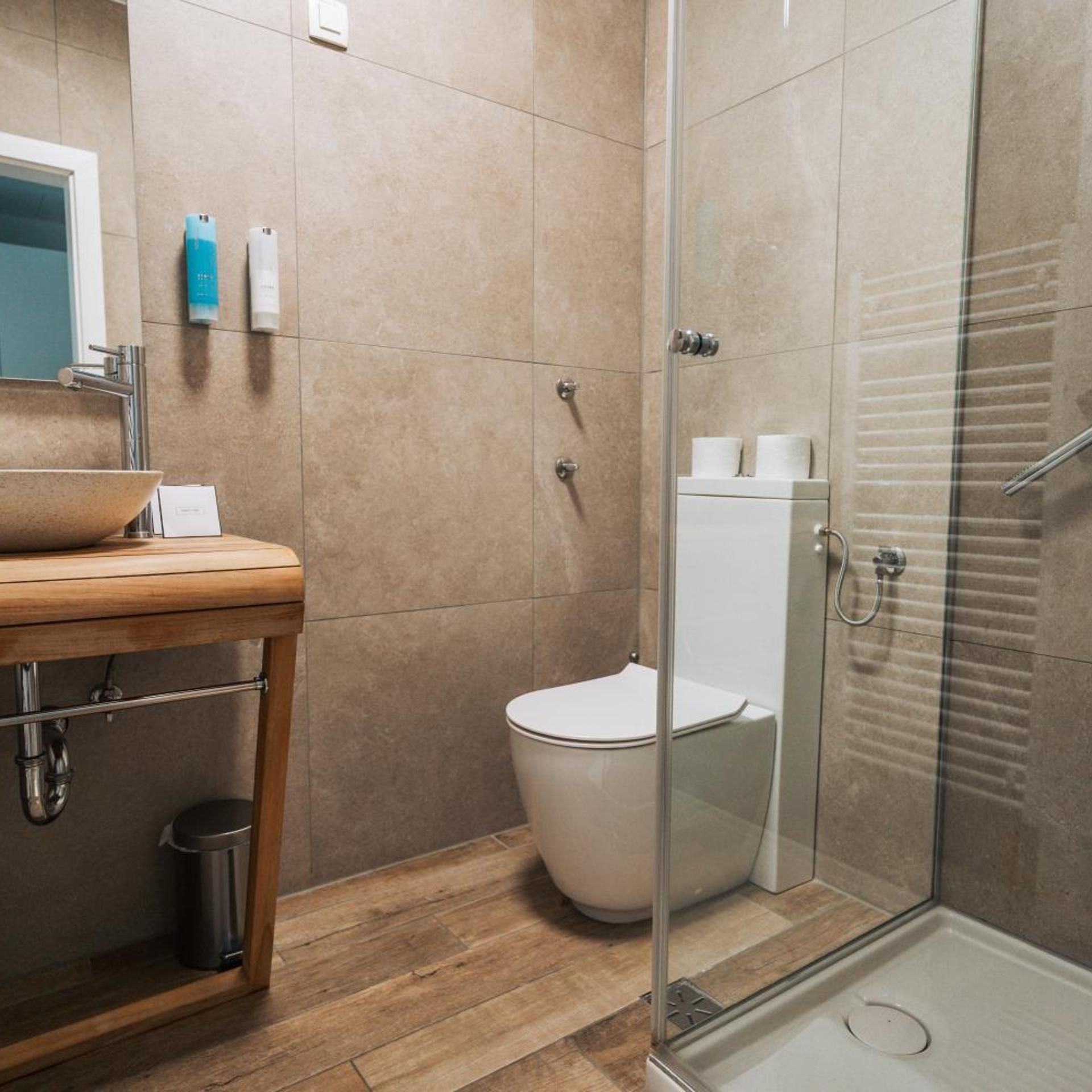 Un baño con tocador de madera, cabina de ducha de vidrio y un inodoro.