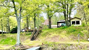 Un chalet au bord du lac, doté d’un quai, entouré d’arbres et agrémenté d’une petite terrasse.