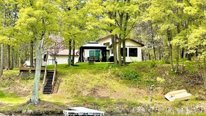 Un chalet au bord du lac, doté d’un quai, et entouré d’une végétation luxuriante et d’arbres.