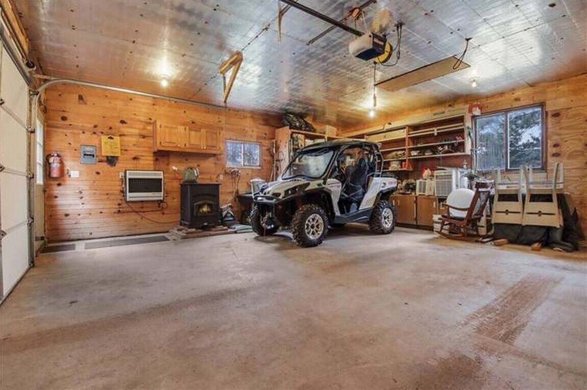 A garage with a vehicle, wooden walls, a television, and a fireplace.