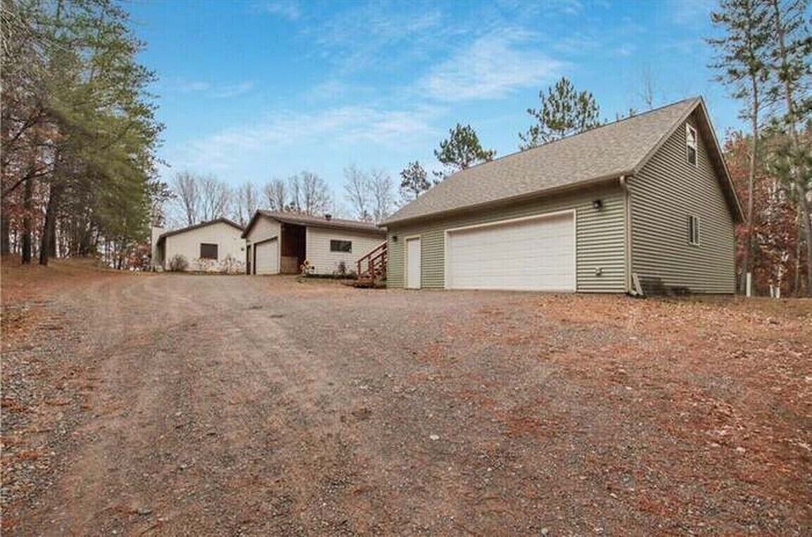 A two-story house with a garage, a covered driveway, and a gravel front yard.