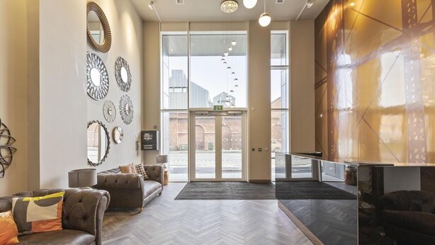 A lobby with a herringbone floor, leather sofas, and a glass door leading outside. - 5* Luxury, City Centre, Brand New Development (Belfast)