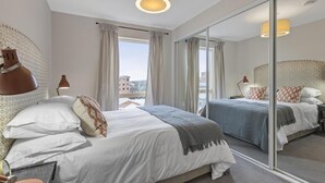 A hotel room with a large bed, a mirror, and a view of the city. - 5* Luxury, City Centre, Brand New Development (Belfast)