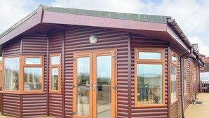 Une cabane en bois dotée de grandes fenêtres et d’un balcon.