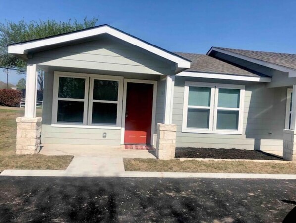 A single-story house with a gabled roof, a front porch, and a red door.