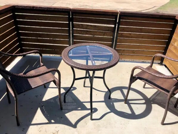 Relax in a serene outdoor seating area with a round table and two comfortable chairs.