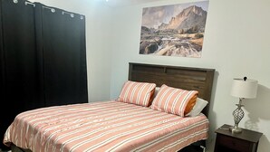 A bedroom with a bed, a nightstand, a lamp, and a painting on the wall. - Elegant 2 Bedroom Apartment Home (Wylie)