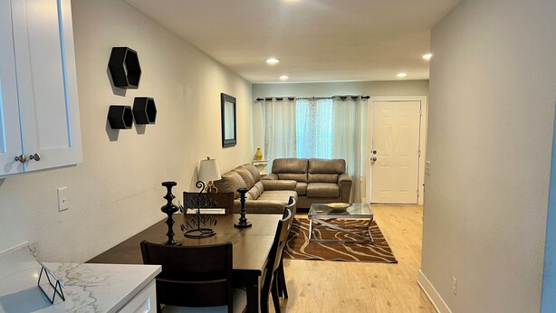 A compact living space with a dining area, a sofa, and a kitchen counter. - Elegant 2 Bedroom Apartment Home (Wylie)
