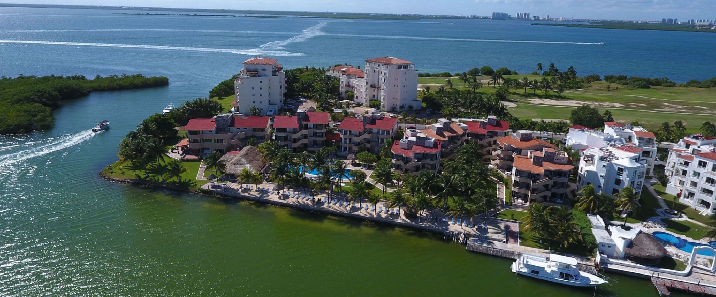 An aerial view of a coastal hotel with multiple buildings, a marina, and a golf course.