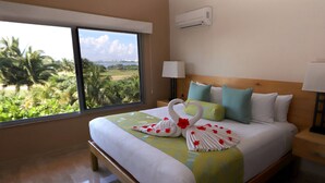 A hotel room with a large window, a neatly made bed, a bedside table with a lamp, and an air conditioning unit on the wall.