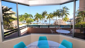 A corner room with a glass wall, a round table, and four turquoise chairs.