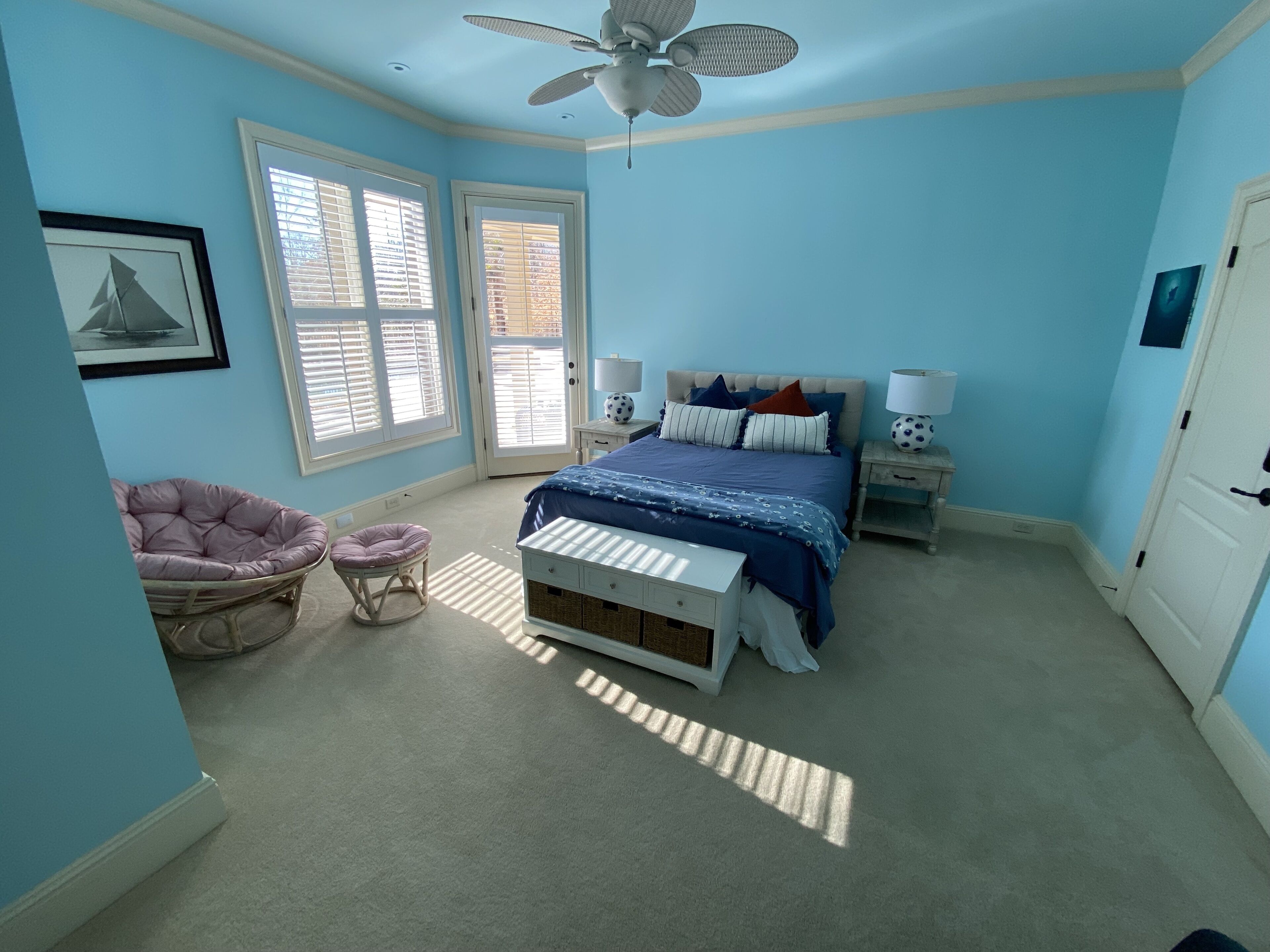 A bedroom with a bed, a chair, a nightstand, and a ceiling fan.