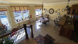 A spacious kitchen with a dining area, wooden staircase, and a view of the outside. - Private Vacation Resort:  Pool,  Spa, Gym, Kitchen, Laundry, in Tranquil Setting (Sugar Hill)