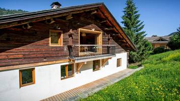 Eine Holzchalet mit Balkon, weißen Wänden und einem Steinweg, der zum Eingang führt.