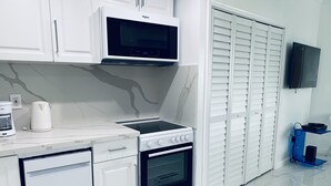 A modern kitchen with white cabinetry, a microwave, a stove, and an oven. - CHARMING BRIGHT Ocean front - view  jacuzzi oven SoBe (Miami Beach)