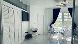 A room with a white ceiling fan, a TV mounted on the wall, a white door, and a table with chairs. - CHARMING BRIGHT Ocean front - view  jacuzzi oven SoBe (Miami Beach)