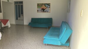 A room with a teal sofa, a small table with a red tablecloth, and a door with a glass panel. - Hotel El Broche (Yopal)