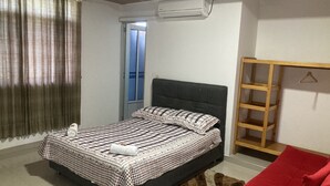 A bedroom with a bed, a wardrobe, a window with curtains, and an air conditioning unit. - Hotel El Broche (Yopal)