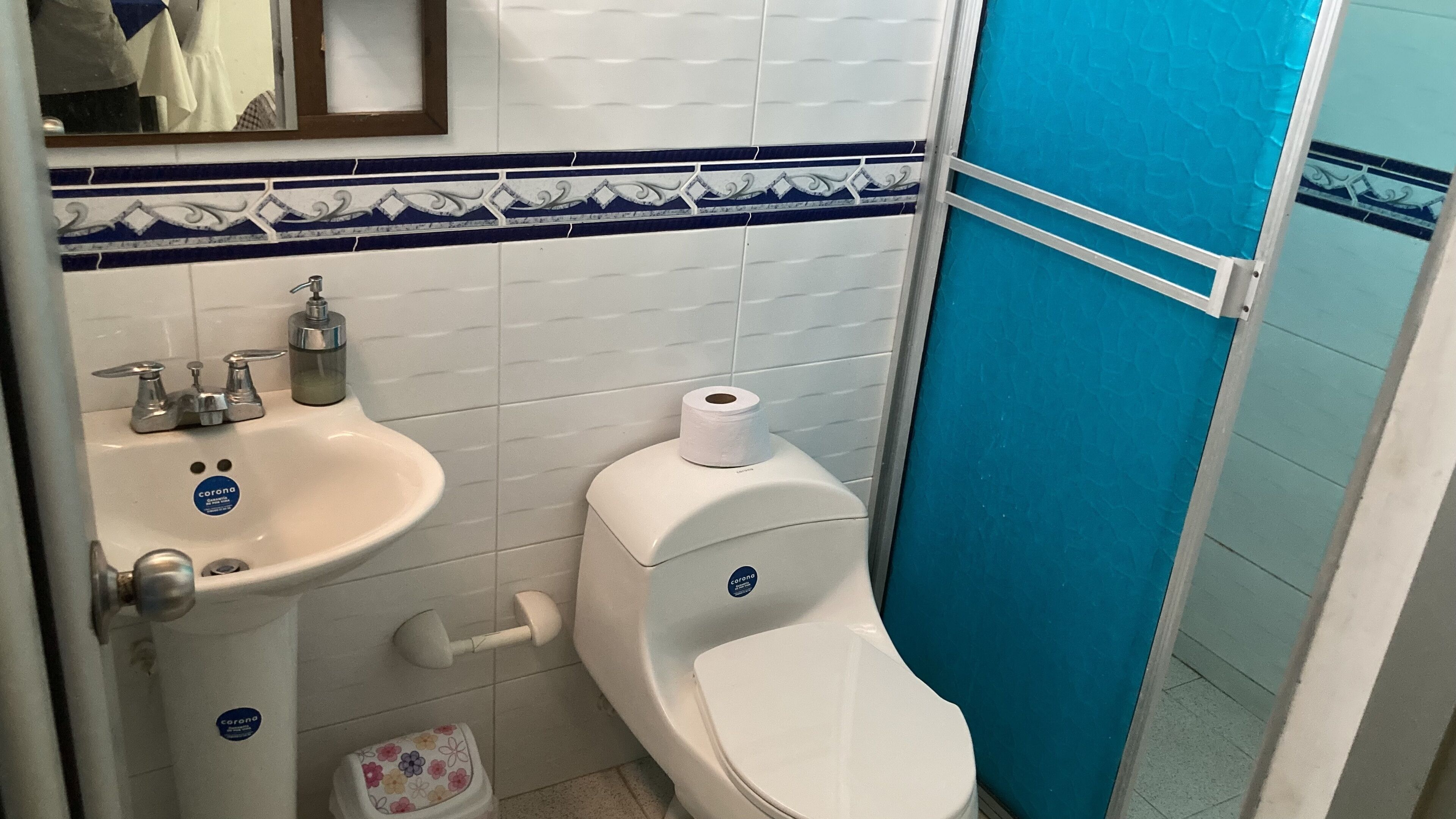 Un baño con un lavamanos blanco, un inodoro y una pared con azulejos azules.