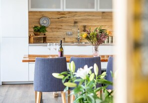 A modern kitchen with wooden cabinets, a built-in wine cooler, and a dining area with blue chairs.