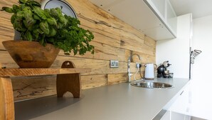Une cuisine moderne avec un revêtement mural en bois, un évier, une machine à café et une plante dans un bol en bois.