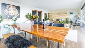 Un salon moderne avec une table à manger en bois, des canapés bleus et un fauteuil suspendu.