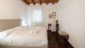 A bedroom with a large bed, a wooden ceiling, a desk, and a chair.