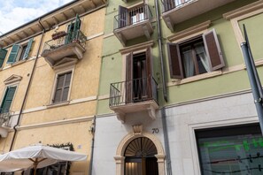 Un immeuble à plusieurs étages, doté de balcons, avec le numéro de porte 70 bien visible et une fenêtre avec des volets.