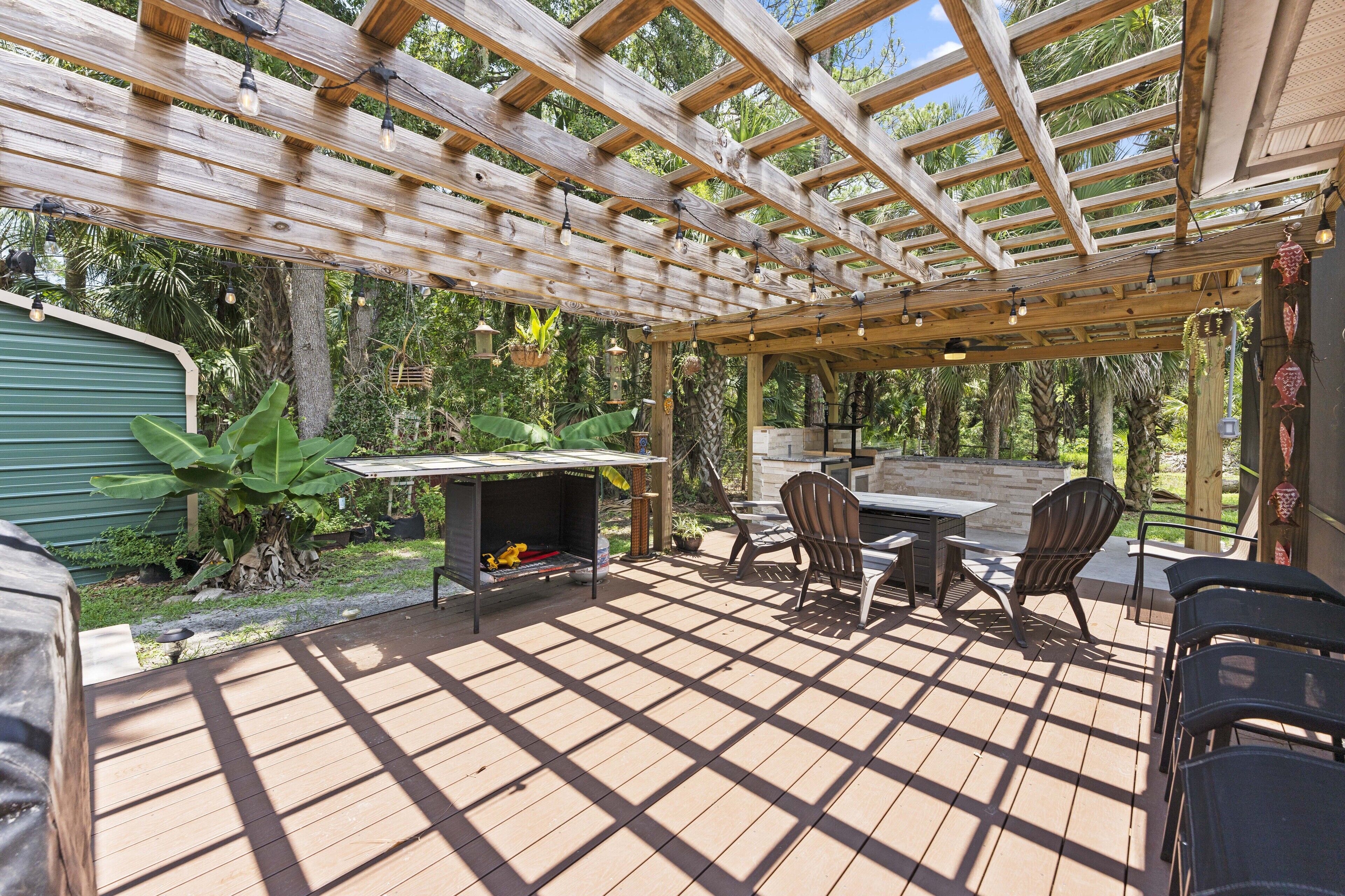 An outdoor patio with a wooden pergola, seating area, and a barbecue grill.