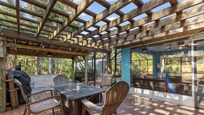 A covered patio with a wooden table and chairs, a glass enclosure, and a view of the outdoors. - Country Oasis w/ Heated Pool > Cocoa FL (Cocoa)