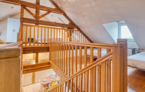 A wooden staircase leading to a loft bedroom with a sloped ceiling, a dining area below, and a window providing natural light. - Lovely home in Jumilhac-Le Grand (Jumilhac-Le Grand)