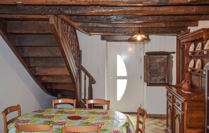 Et spiseområde med en trætrappe, et bord med farverigt borddække og et skab med pynteting.
