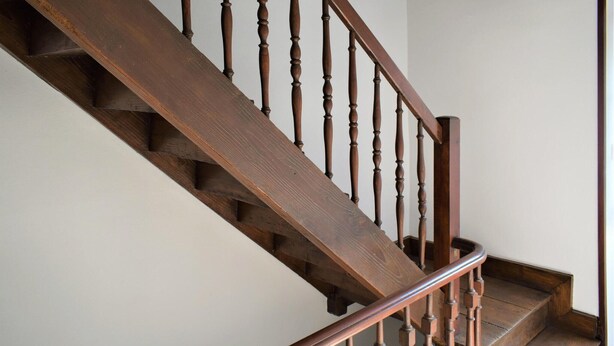 Un escalier en bois avec une main courante et des balustres.
