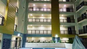 A multi-story building with a central courtyard featuring a swimming pool. - Private Cozy Spacious Condo Unit with Gym— Walk distance to market (Los Angeles)