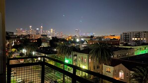 A nighttime cityscape with a view of a densely packed urban area, including various buildings and palm trees. - Private Cozy Spacious Condo Unit with Gym— Walk distance to market (Los Angeles)